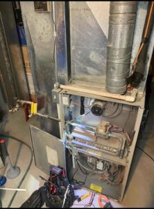 Severely dirty, water-damaged furnace interior showing clogged burners and rust