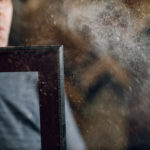 Man blowing dust off a picture frame, showing poor indoor air quality and airborne particles