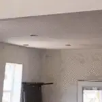 Newly installed drywall and textured walls in a historic home renovation, showing fresh white surfaces and open framed spaces.