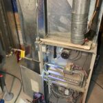 Severely dirty, water-damaged furnace interior showing clogged burners and rust